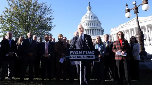 A group of people in suits standing behind a sign that reads "Fighting retail crime." The U.S. Capitol is in the background.