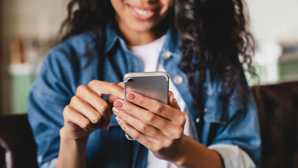 Smiling young woman using smart phone at home