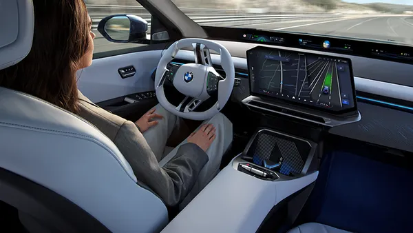 A driver using a hands-free driving system in the new BMW iX3 electric vehicle.