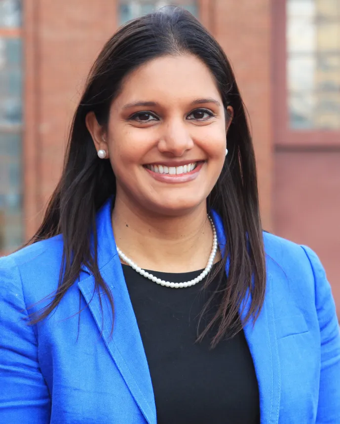 Woman with long black hair in a blue suit.