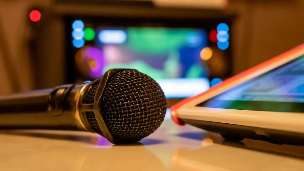 Image of a karaoke microphone and remote control on a table.