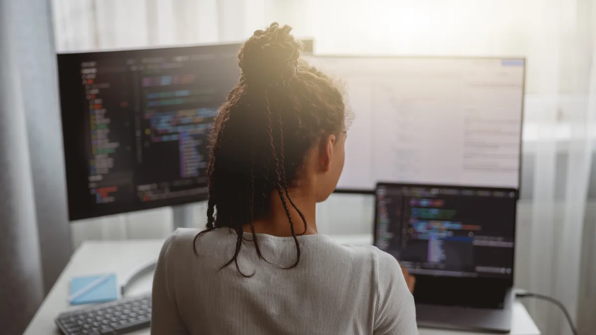 Close up of happy IT worker coding on computer at home looking at monitor