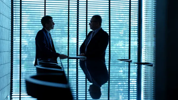 Two businessmen meet in a conference room.