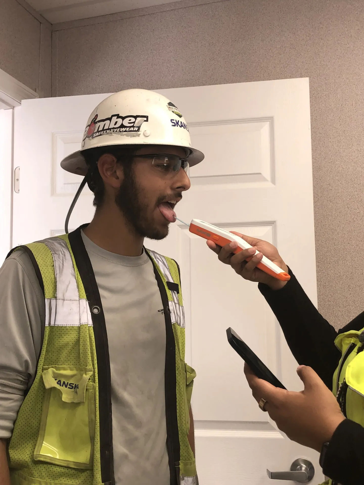 A construction worker sticks their tongue out for a medical test.