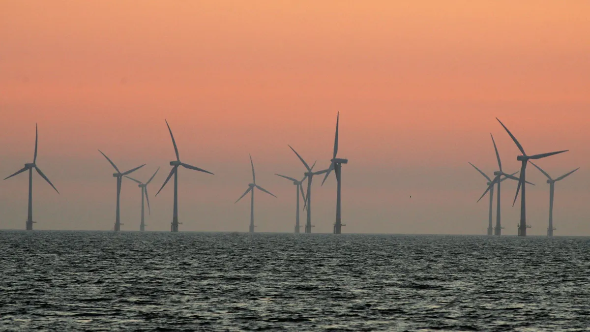 The sun starts to rise behind Britain's largest offshore wind farm off the Great Yarmouth coastline on July 19, 2006 in Norfolk, England.