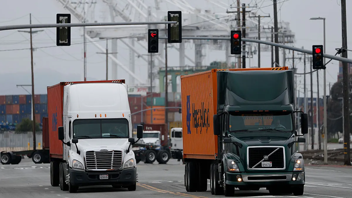 Trucks carrying shipping containers pass through traffic lights.