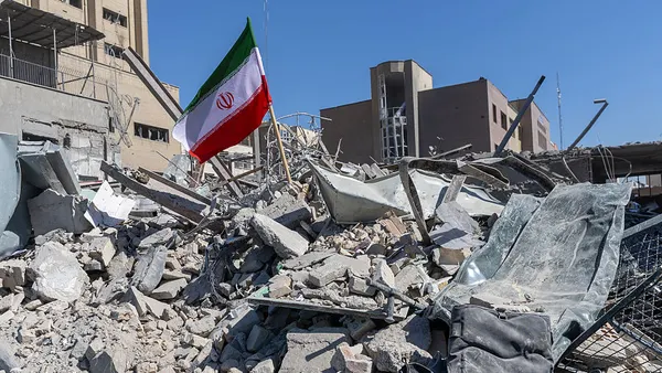 A pile of rubble with an Iranian flag stuck in it is shown.
