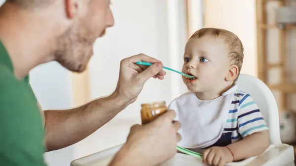 A parent feeds baby food to an infant