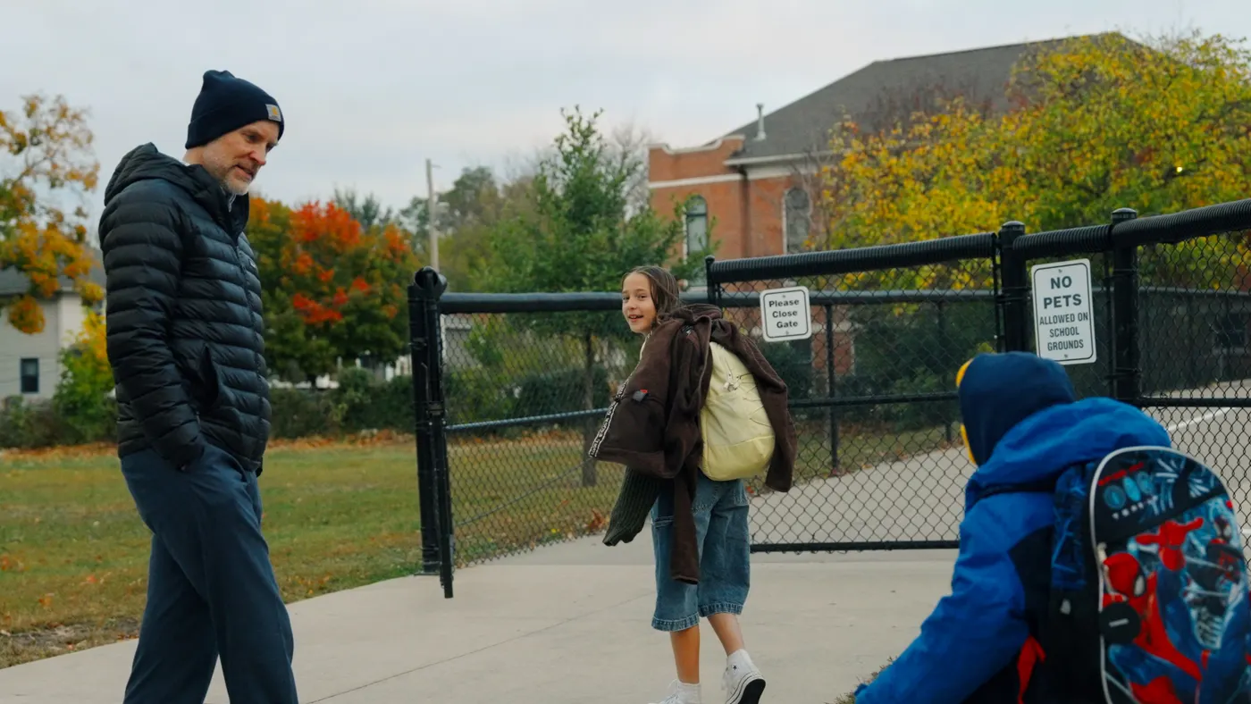A superintendent greets elementary students outside of their school as they arrive on a fall morning.