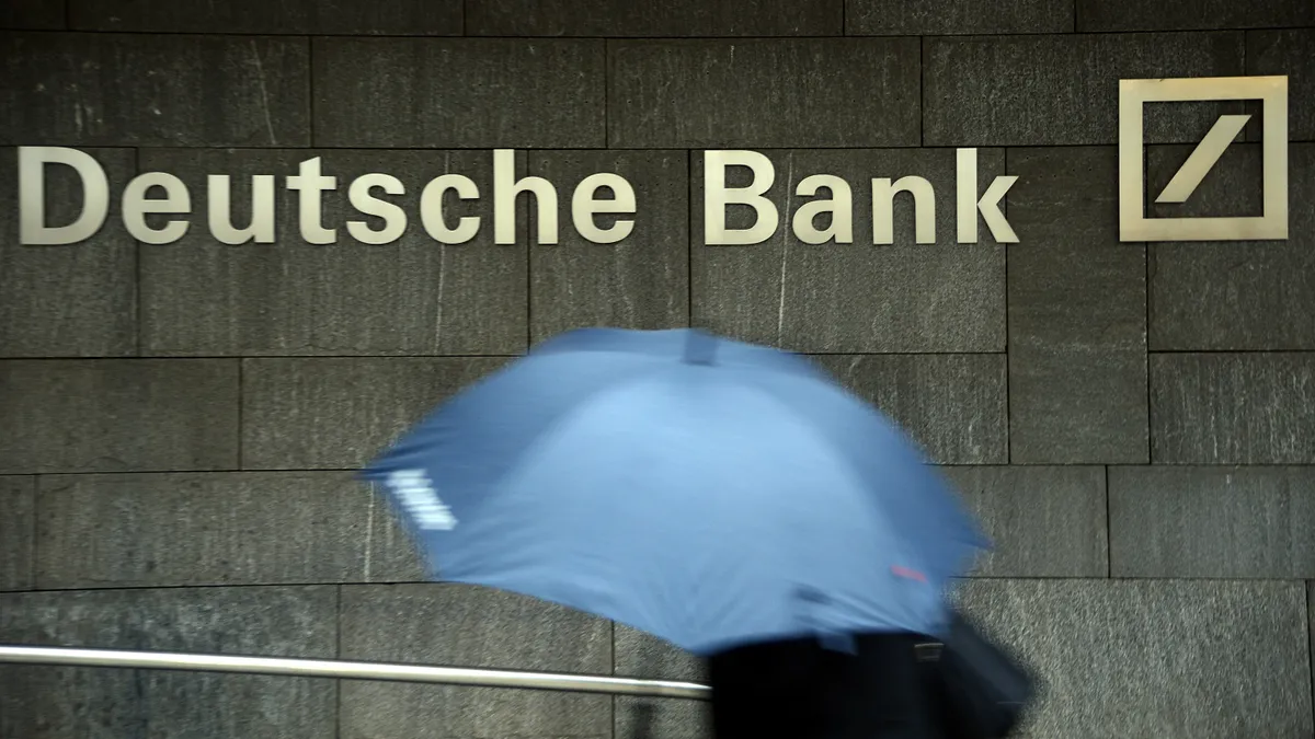 Person with umbrella passing Deutsche Bank