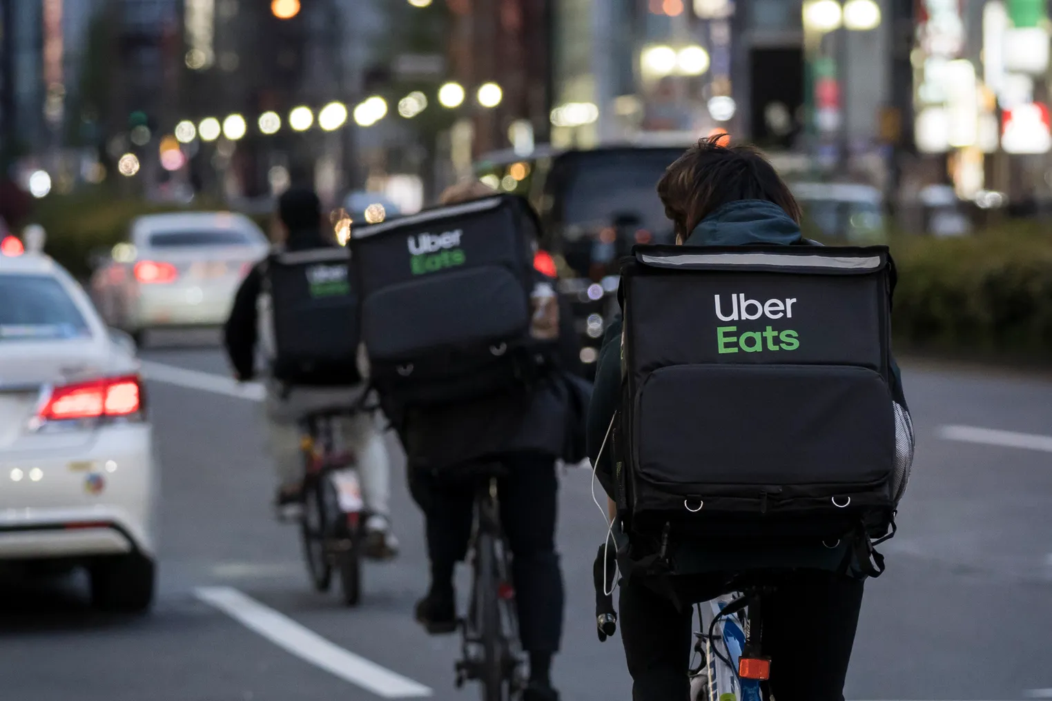 Backs of bike couriers with Uber Eats bags.