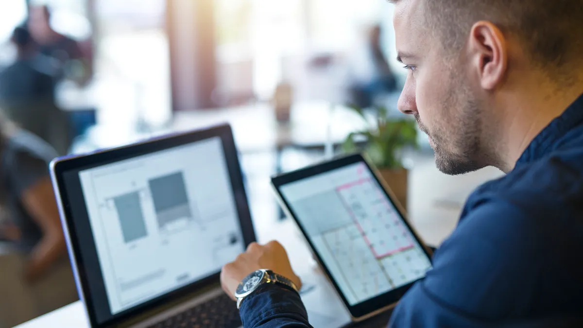 Business man looking and analyzing projects on his laptop computer and tablet.