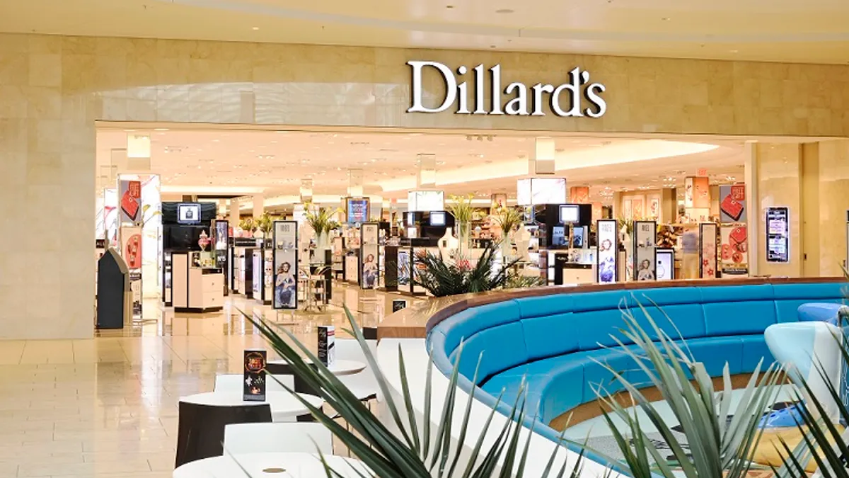 A store's mall entrance, with a plant in the foreground.