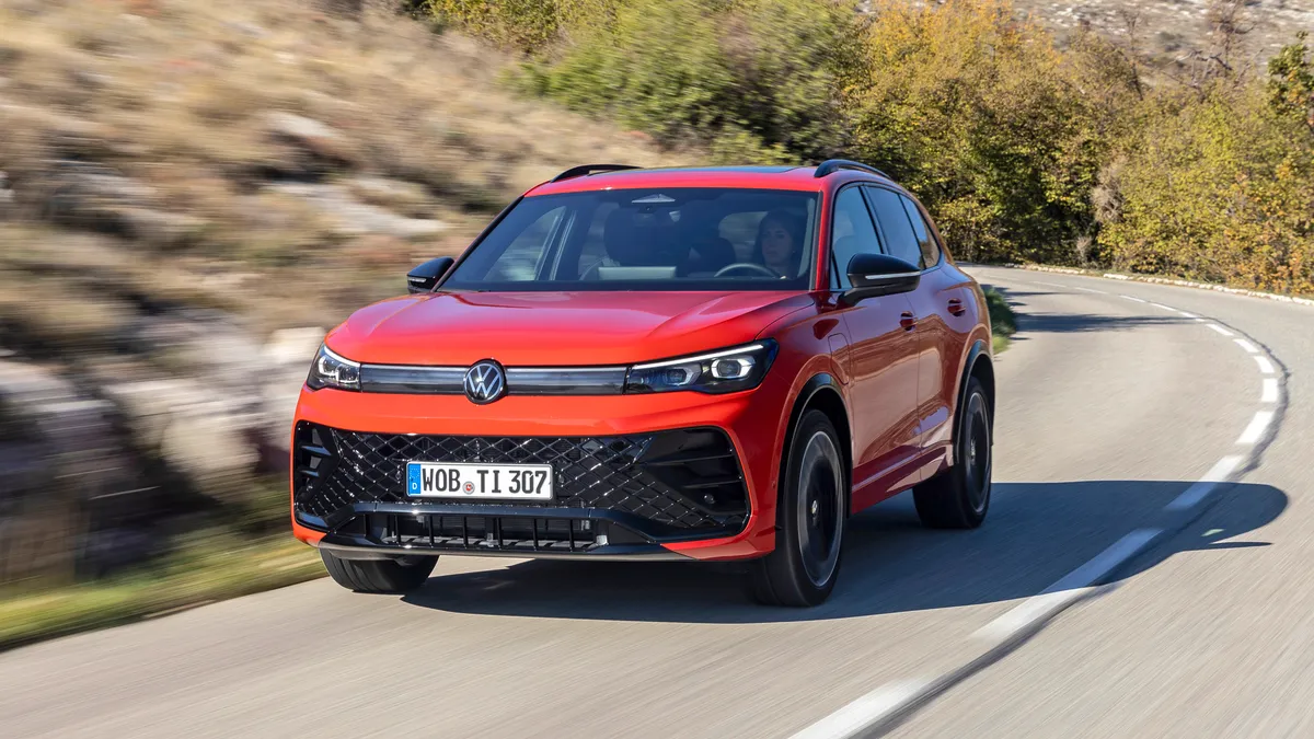 A red 2024 Volkswagen Tiguan SUV driving on a highway.