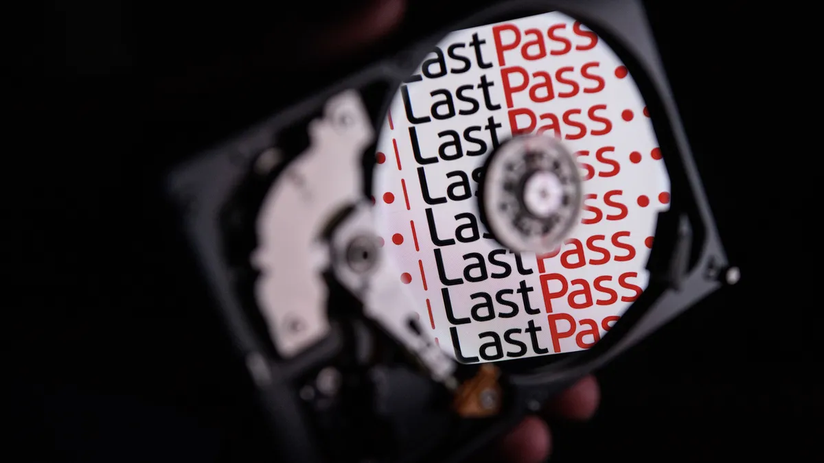 A photo illustration of LastPass logos on a hard drive disk held in someone's hand.