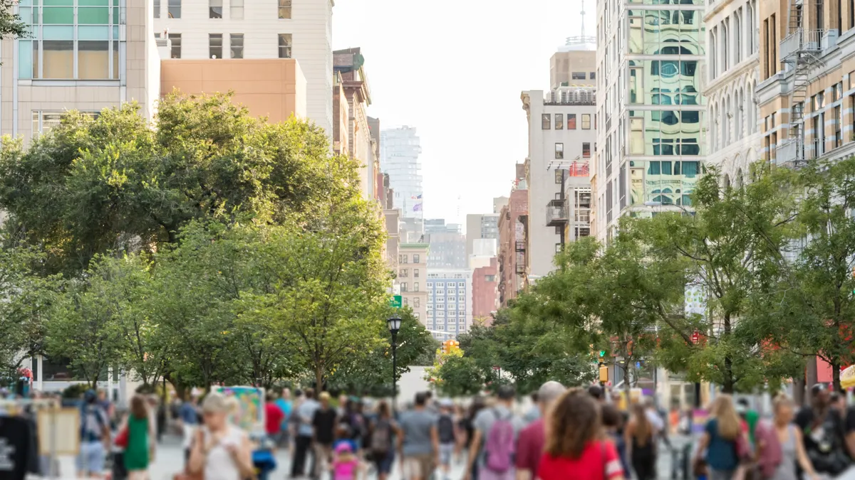 Crowds of people walking through Union Square Park in Manhattan New York City on a bright sunny day.