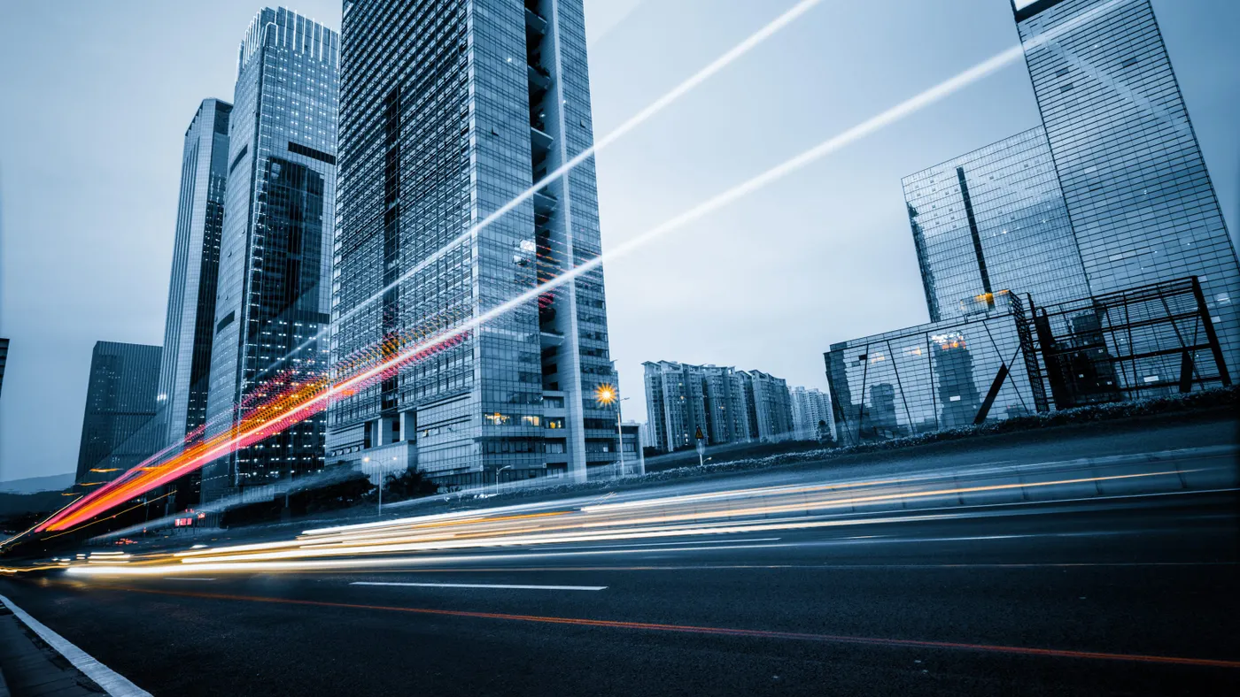Car lights speeding past city buildings