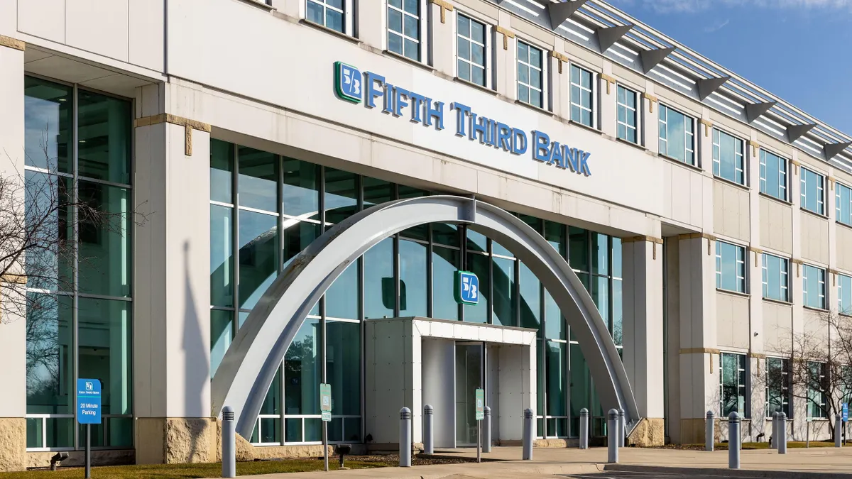 A modern glass arched facade with a Fifth Third Bank sign is displayed above the revolving door entrance. 