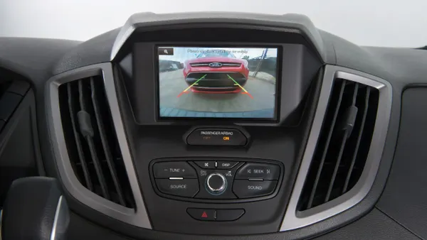 The center display in a 2017 Ford Transit van showing a red vehicle on the screen.