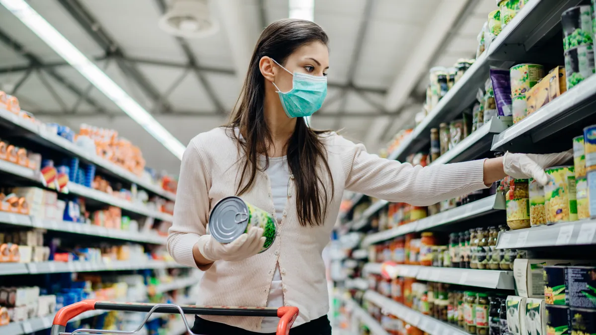 Woman preparing for pathogen virus pandemic spread quarantine.Choosing nonperishable food essentials.Budget buying at a supply store.Pandemic quarantine preparation.Emergency to buy list - stock photo