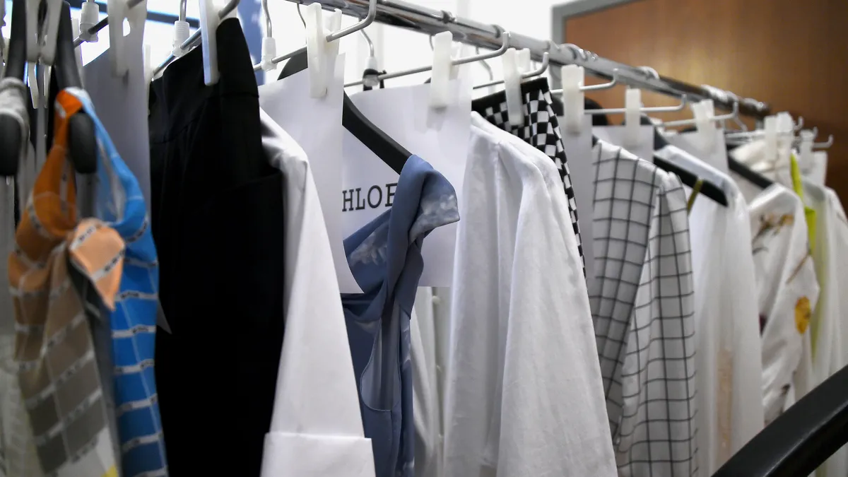 Clothes of various styles and colors hang on hangers on a clothing rack during New York Fashion Week.