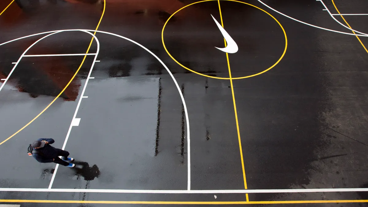 A Nike employee talks and walks on a Nike-branded, black basketball court