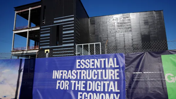 A sign that says "Essential Infrastructure for the Digital Economy" hangs on a construction site.