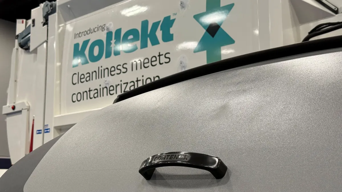 A large bin with a lid and a handle that reads "Contenur" is in the forgeround, while a truck with branding for "Kollekt" is behind it.
