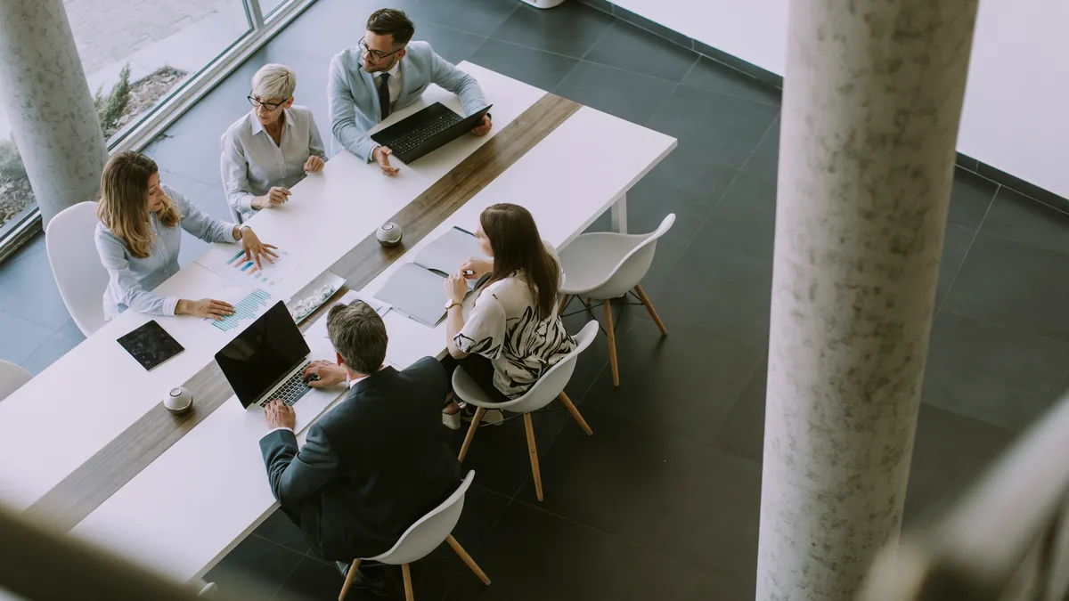 Five people sit at a table for a business meeting.