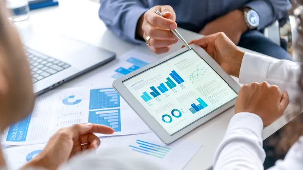 a work station with digital graphs in the center, featuring executives all around