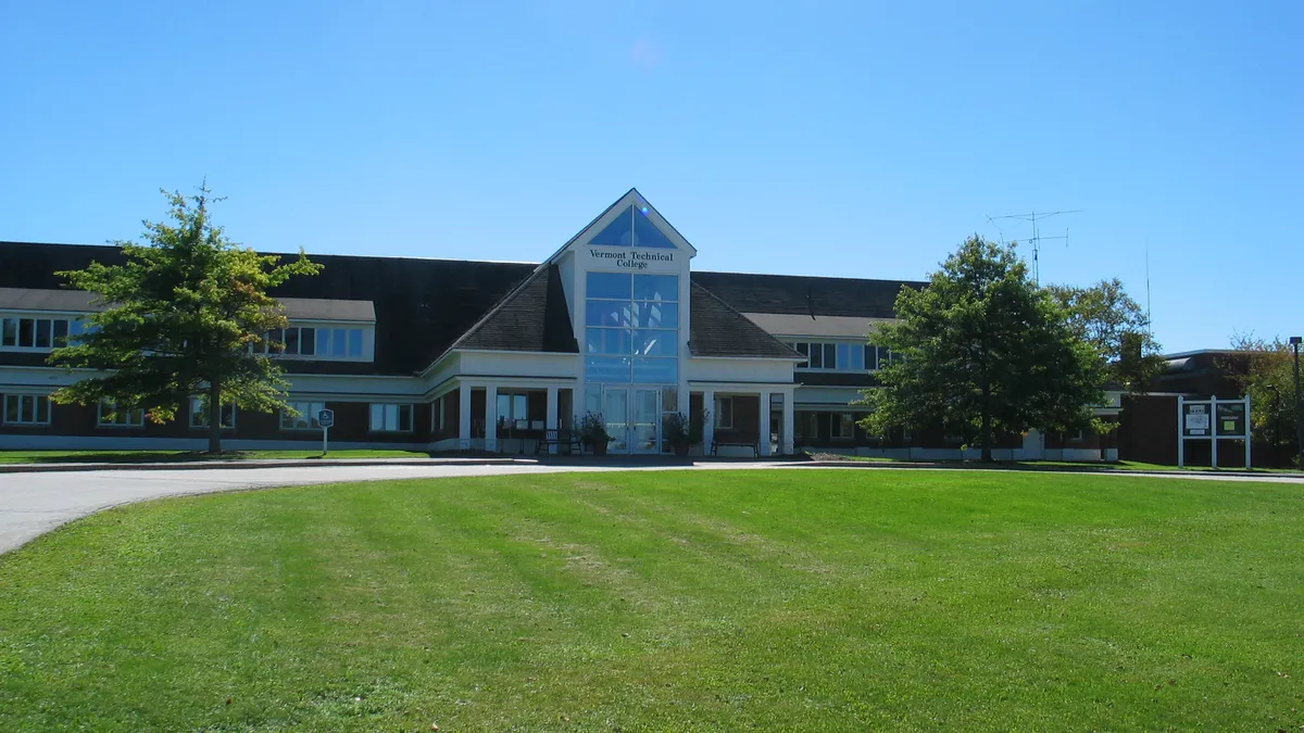 A building sits behind a lawn.