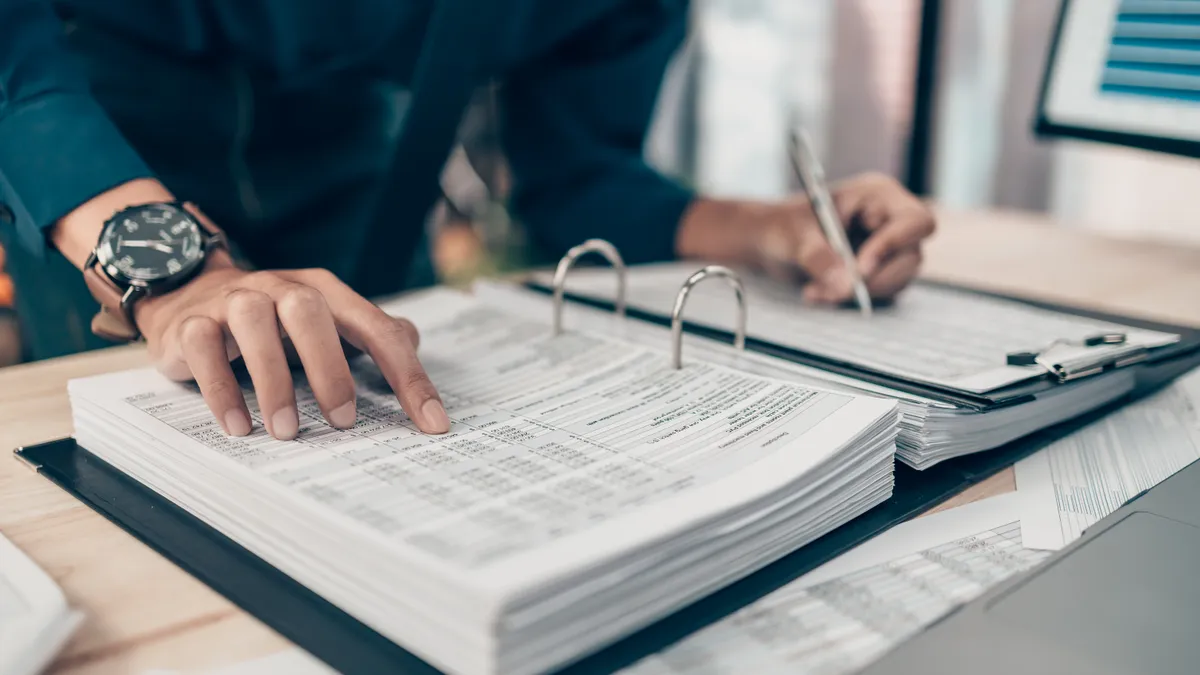 Business person examines a binder with data.