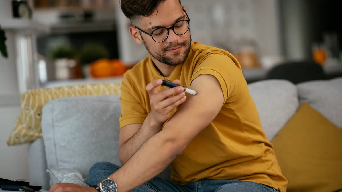 A man gives himself an insulin shot at home.