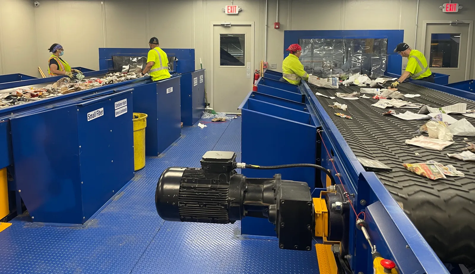 Workers in yellow uniforms stand over conveyor belts