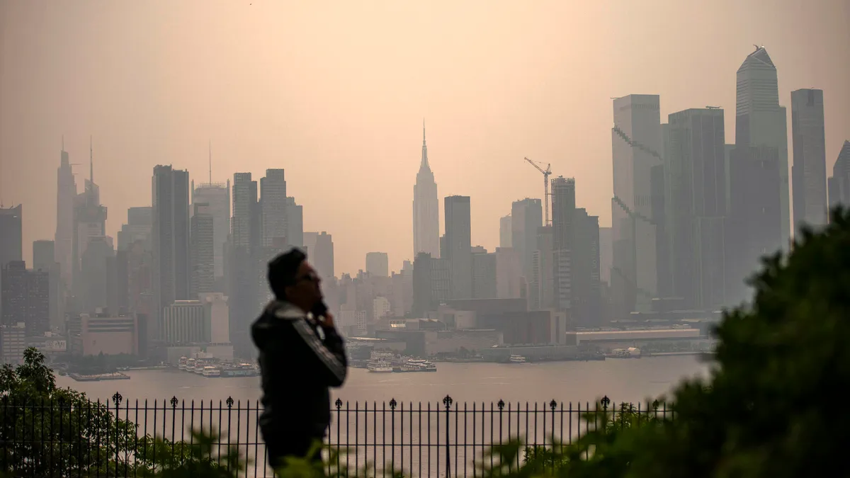 A person silhouetted against a hazy city skyline