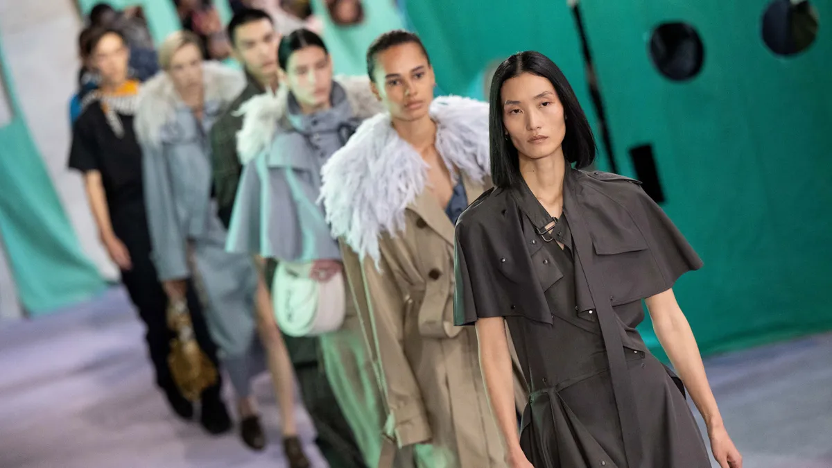 Models walk down a runway wearing outerwear.