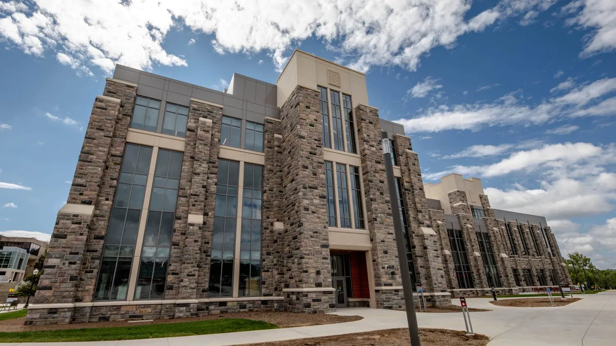 A large, stone building looms in the center of the photo, comprised of brown stones and glass windows.