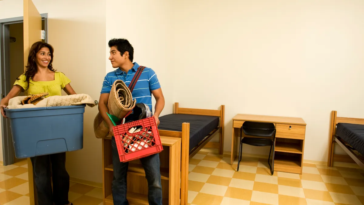 A mother helps her son move into his college residence hall.