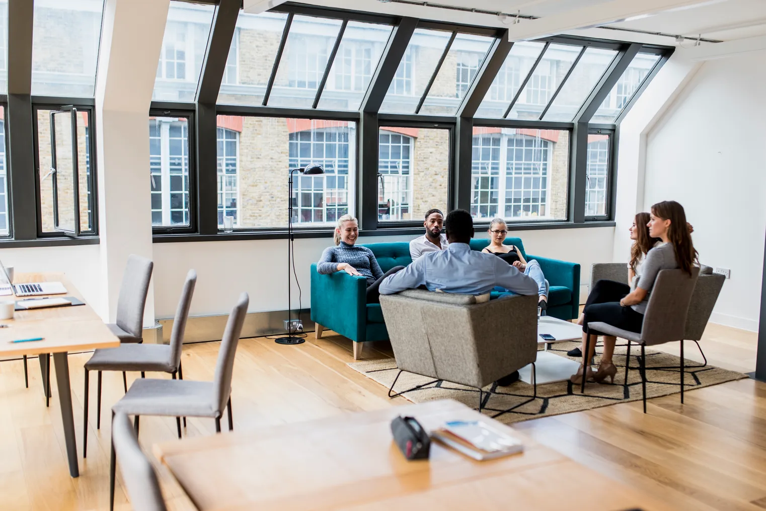 Businesspeople discuss their future plans in the office on a couch and lounge chairs.