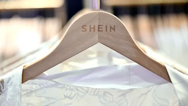 A white dress hangs on a hanger with a Shein logo.