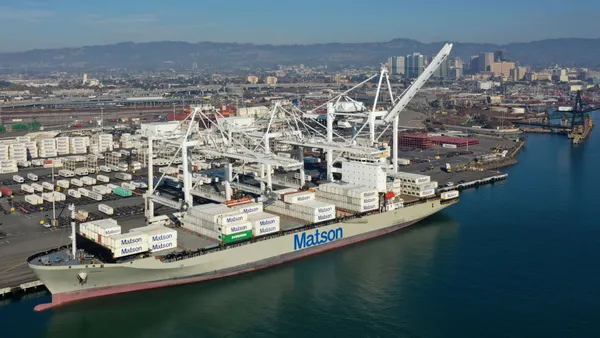 A white container vessel docked at an ocean port with the Matson logo.