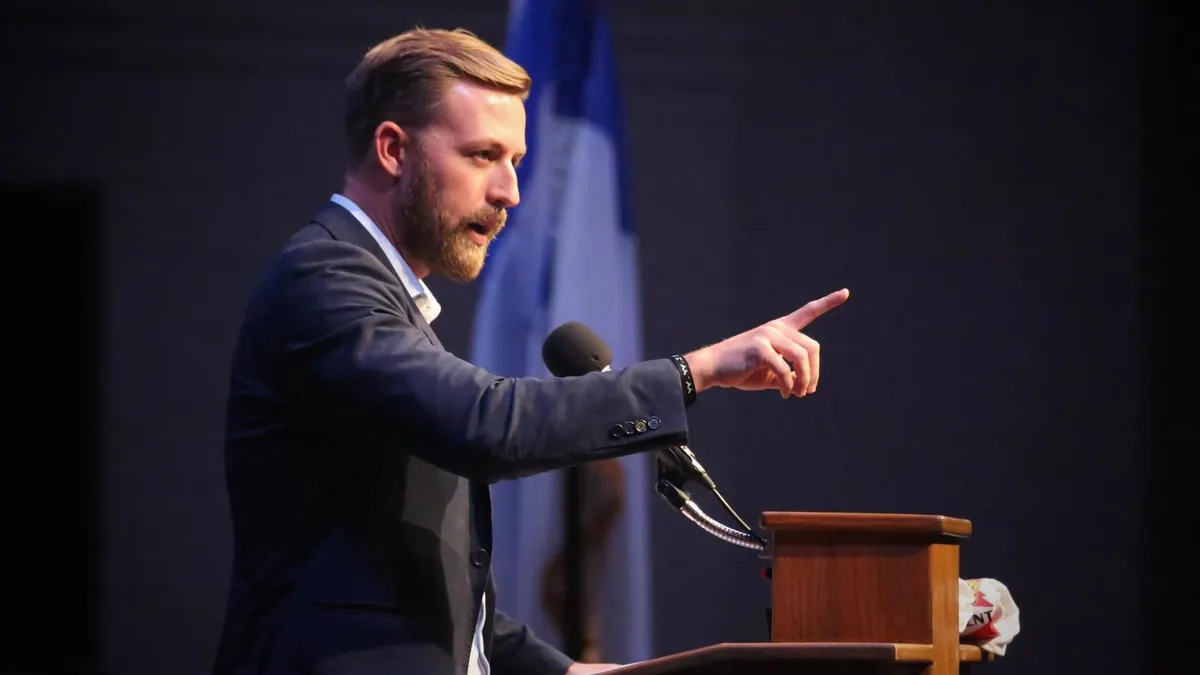 Top Oklahoma education official Ryan Walters speaks at a podium with his hand raised