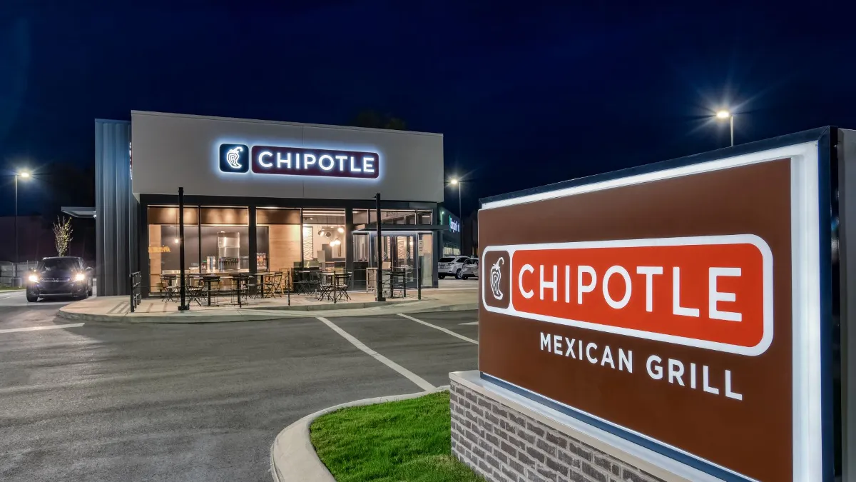 An image of a a white building with Chipotle signage at night.