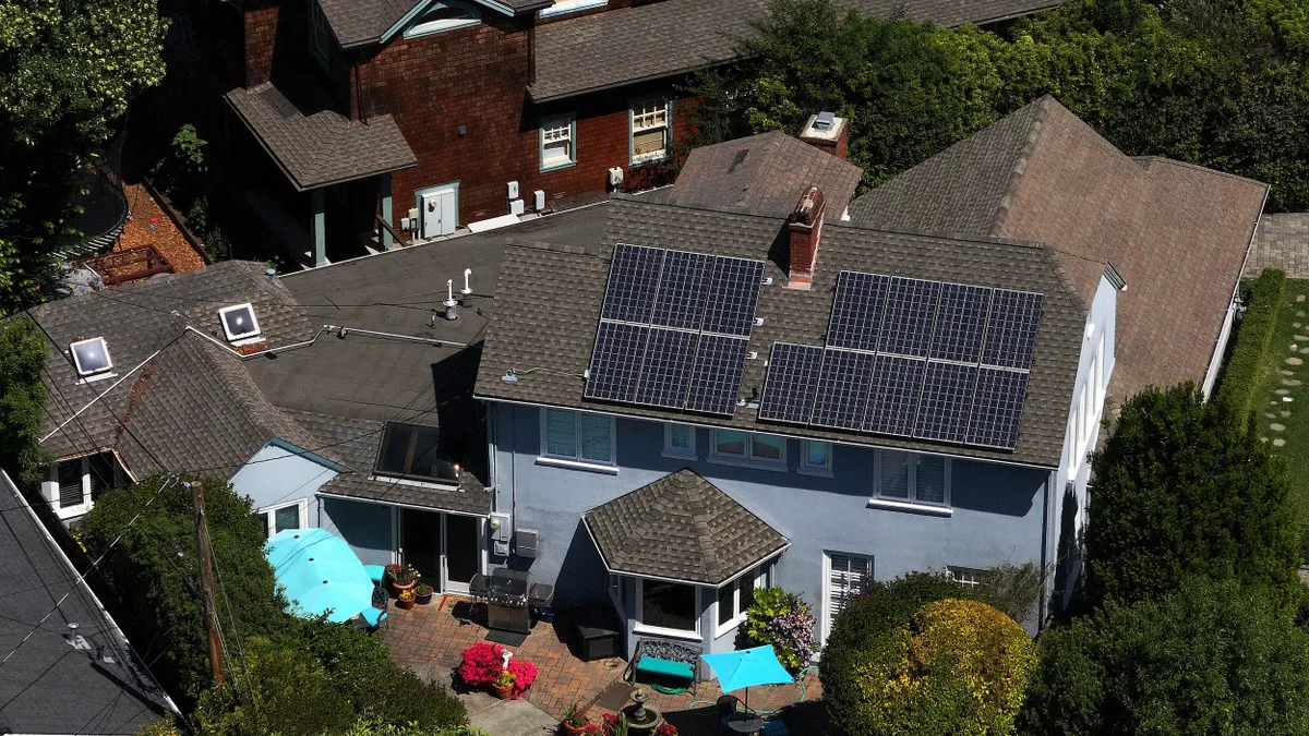 Aerial view of a home with solar panels on the roof and a swimming pool.