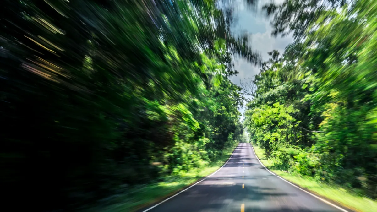 Empty asphalt road and speed motion blur on highway in summer with green trees forest at countryside