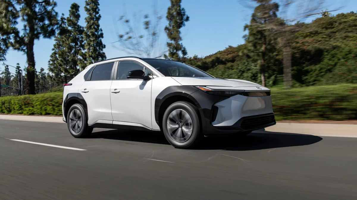 A white Toyota bZ4X electric SUV driving on a road.