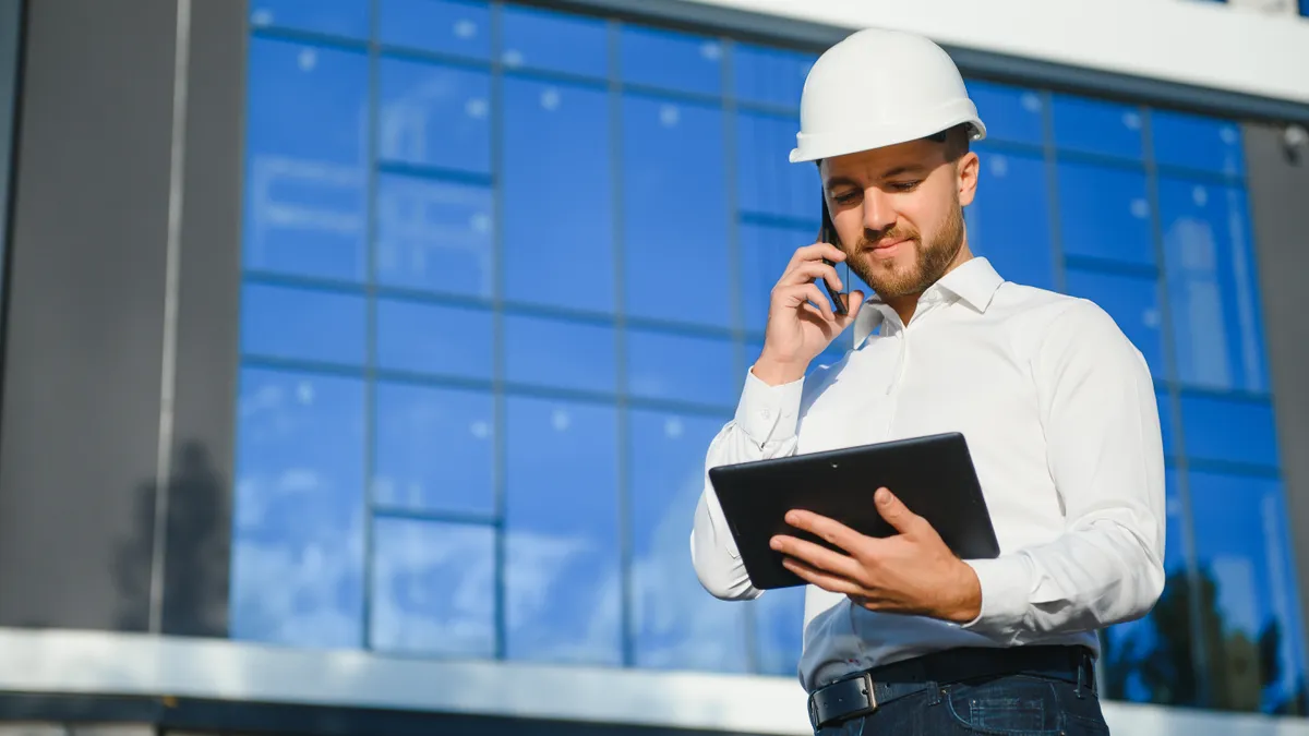 An engineer holds a tablet outside a commercial building.