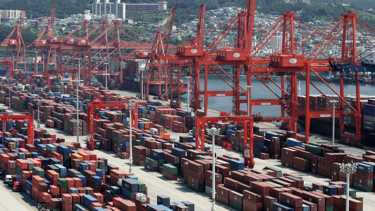 A line of cranes work cargo containers at port.