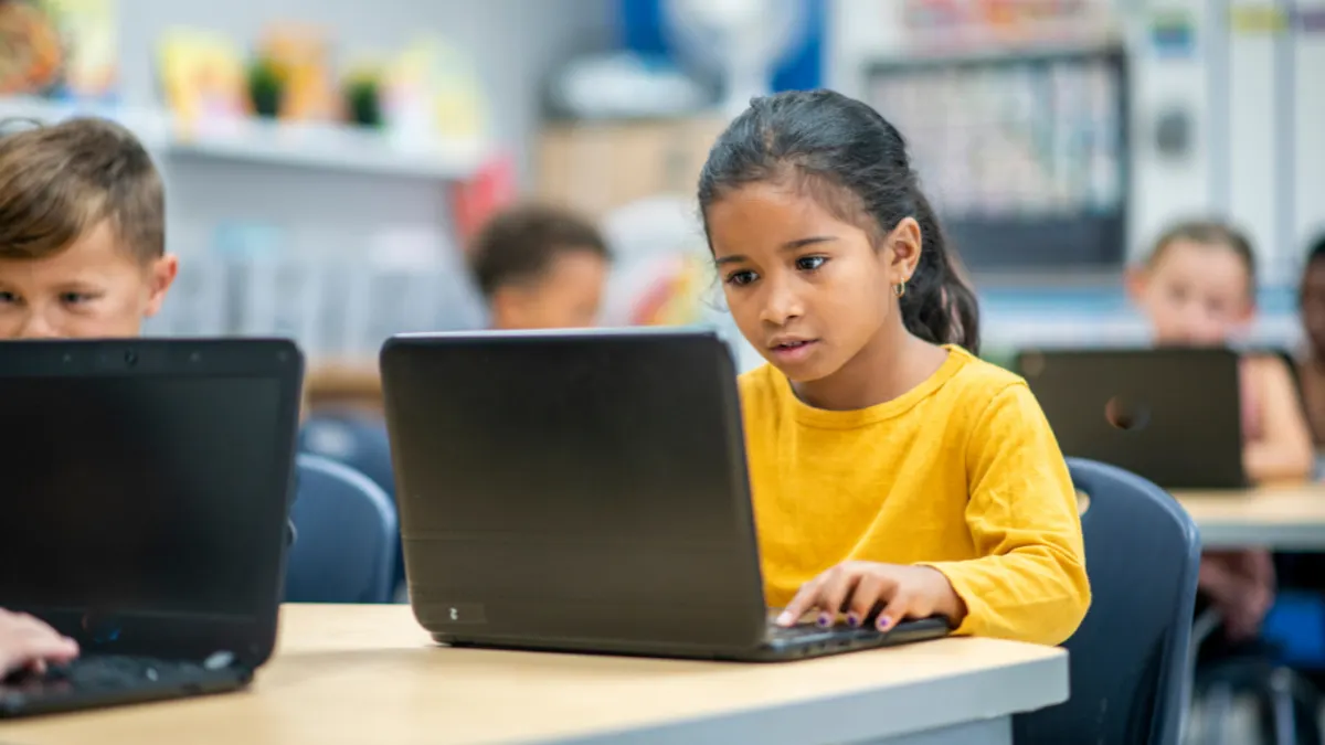 A student working on their laptop in a classroom.