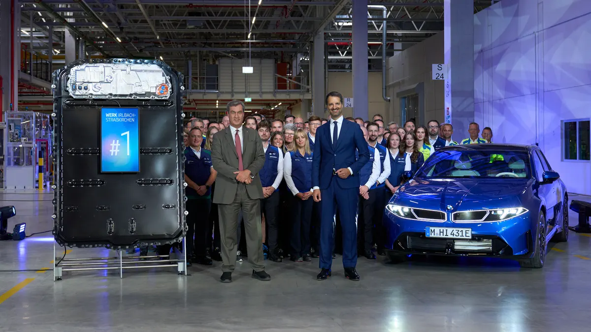 Two executives pose with workers at BMW's new Plant Irlbach-Straßkirchen battery factory in Bavaria to commemorate the start of cell production.